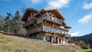 A multi-story wooden chalet with balconies, set on a hillside with a forest backdrop. - Alta Rocca, 14-guest chalet in Gérardmer – pool, jacuzzi, sauna (Gérardmer)