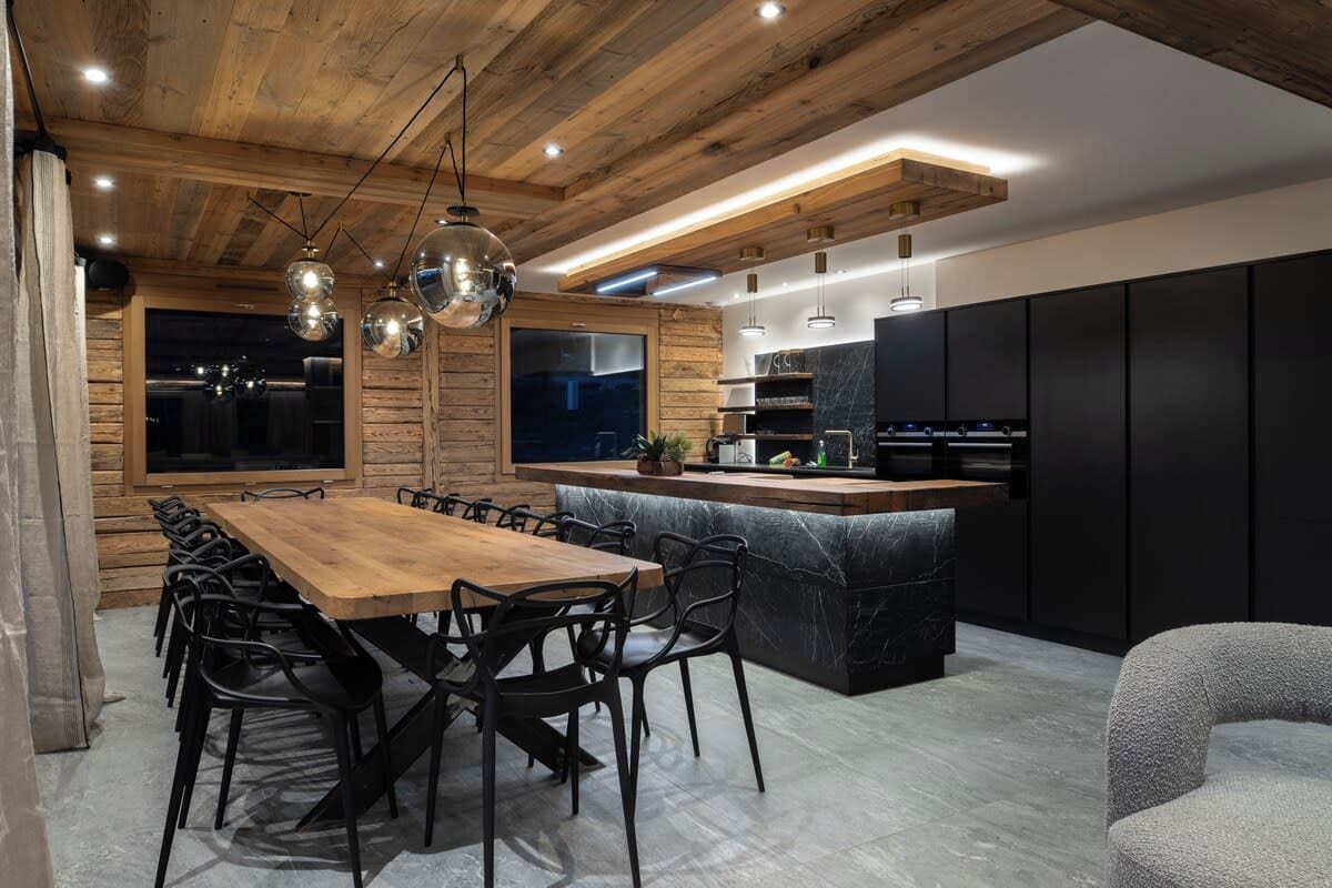 A modern kitchen with a wooden ceiling, black cabinets, and a central island.