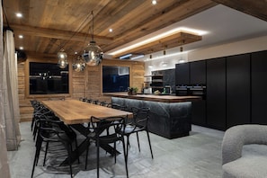 A modern kitchen with a wooden ceiling, black cabinets, and a central island. - Alta Rocca, 14-guest chalet in Gérardmer – pool, jacuzzi, sauna (Gérardmer)