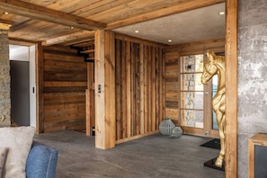 A wooden interior with a stone wall, a large wooden door, and a golden horse statue. - Alta Rocca, 14-guest chalet in Gérardmer – pool, jacuzzi, sauna (Gérardmer)
