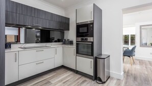 A modern kitchen with grey cabinets, a stainless steel sink, and a built-in oven. - St Meddans Mews in Troon (Troon)