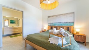 A bedroom with a bed, a painting, a nightstand, and a lamp. - DOMAINE DU FLAMAND - GÎTE LAGUNE (Naujac-sur-Mer)
