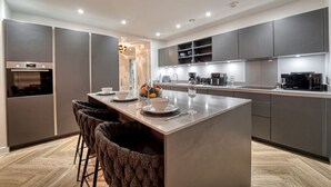 Une cuisine moderne dotée d’un îlot central, de tabourets de bar et d’appareils électroménagers intégrés.