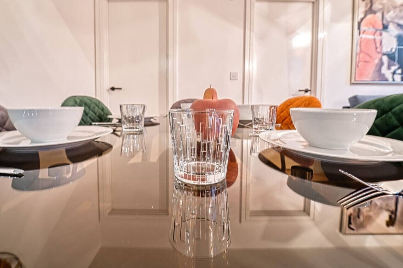 Une table à manger avec de la vaisselle en verre transparent, des assiettes et une décoration centrale en forme de citrouille.