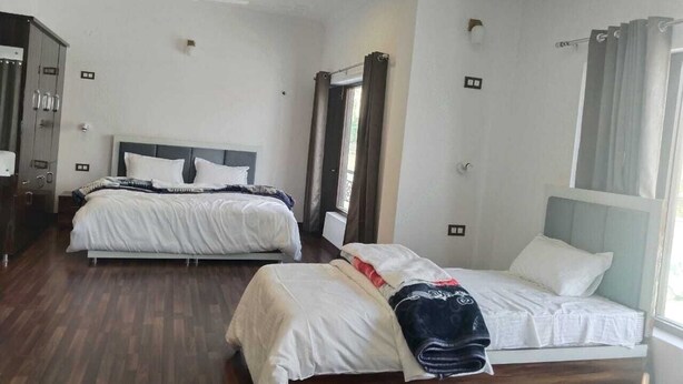 A hotel room with two beds, a wardrobe, and a large window with curtains. - Mount Vista Leh (Leh)