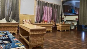 A spacious room with a wooden floor, multiple low tables, and a large bed with a patterned bedspread. - Mount Vista Leh (Leh)
