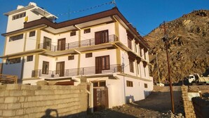 A multi-story residential building with a flat roof, a balcony on the second floor, and a gated entrance. - Mount Vista Leh (Leh)