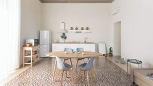 A modern kitchen with a dining area, white cabinets, a microwave, and a sink. - Darsena Apartments by Wonderful Italy (Syracuse)
