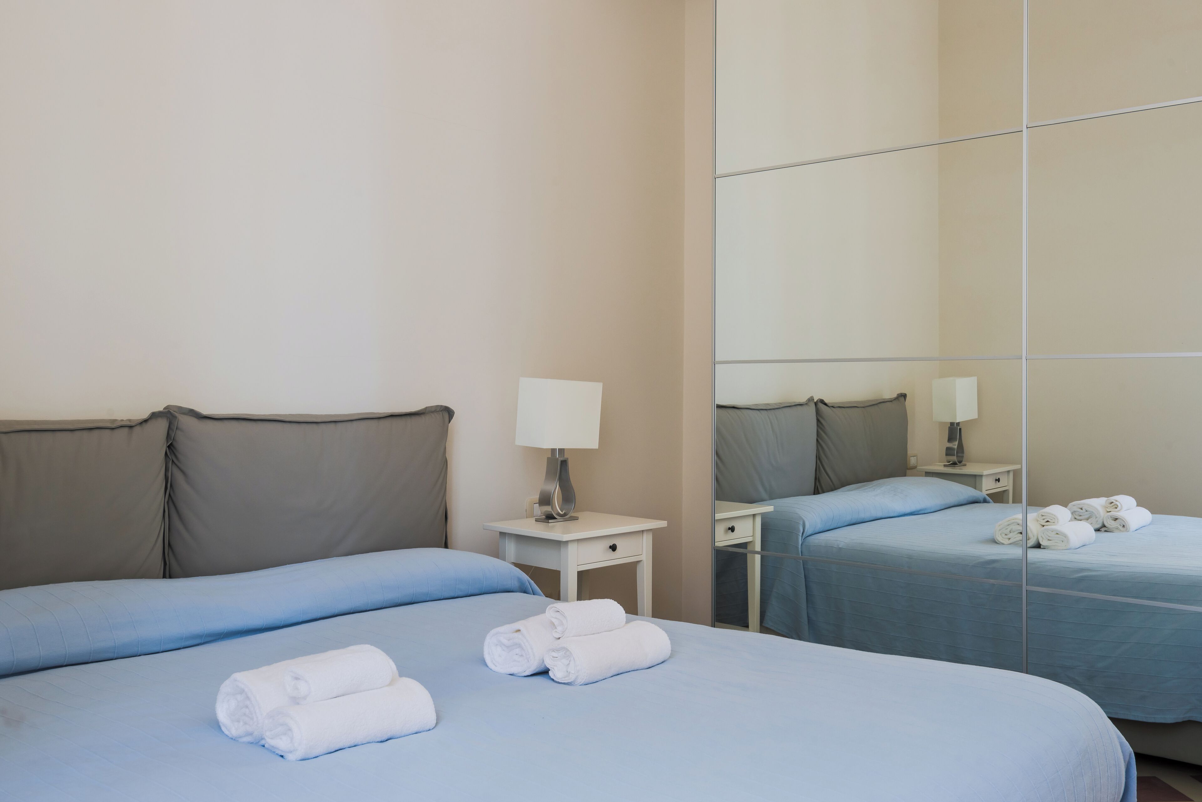Une chambre d’hôtel avec un lit, une table de chevet, un miroir et un mur orné d’un grand miroir.