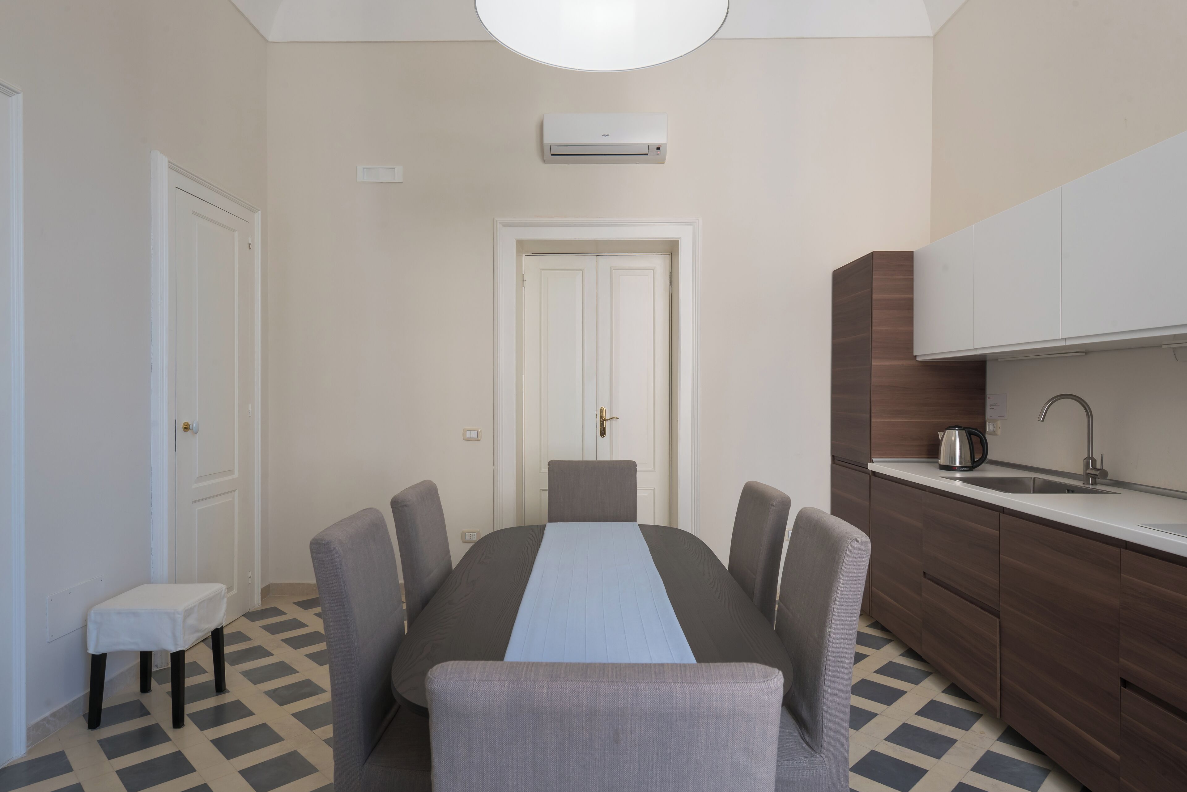 Una cocina compacta con una mesa de comedor, sillas, un taburete pequeño y un horno empotrado.