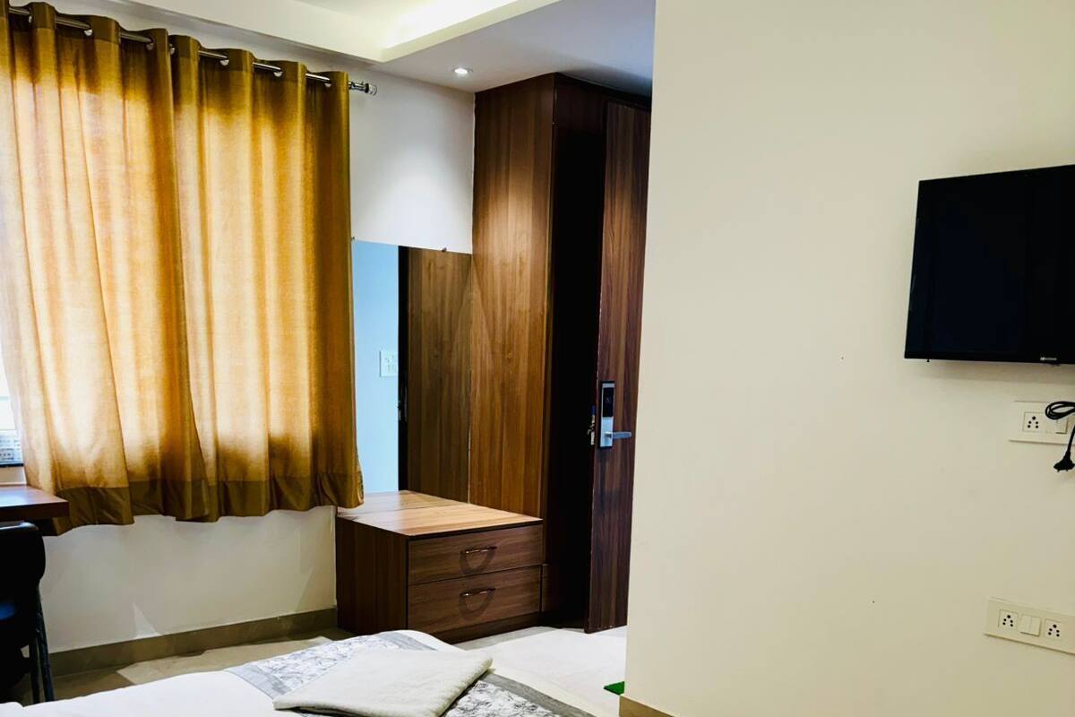 Habitació d'hotel amb llit, escriptori, cadira, televisió i armari.