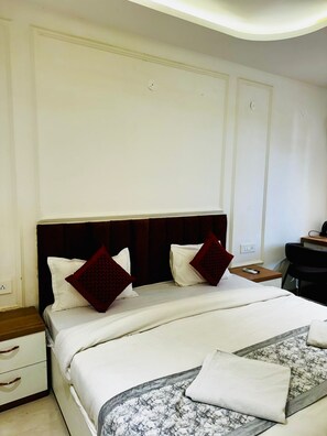 A hotel room with a large bed, two nightstands, a desk, and a chair. - Hotel Prince Inn By DSY Hospitality (Greater Noida)