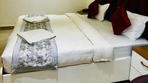 Quarto moderno com cama, mesas de cabeceira e criado-mudo.
