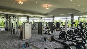 A spacious gym with various exercise equipment, large windows, and a high ceiling. - Sanpudard Health and Wellness Club (Ban Pho)