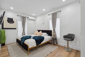 Un dormitorio moderno con una cama, una silla y una planta en maceta.