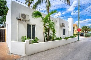 A white building with two air conditioning units, a stop sign, and a palm tree in the foreground. - Casa Roselle 3 Bedrooms Beach access (HOLLYWOOD)