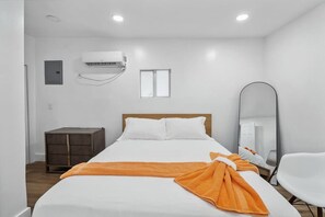 Une chambre d’hôtel équipée d’un lit, d’un climatiseur, d’une petite armoire, d’un miroir et d’une chaise.
