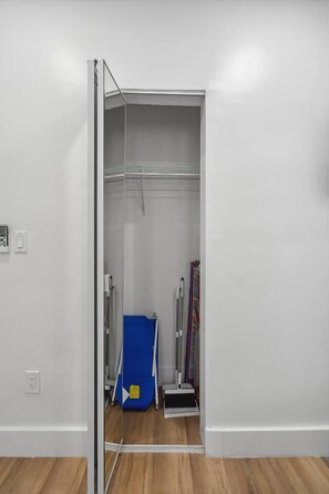 A room with a white wall, a wooden floor, a blue storage unit, and a metal ladder.