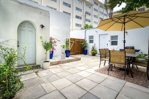 Un patio con mesa y sillas, plantas en macetas y una valla de madera.