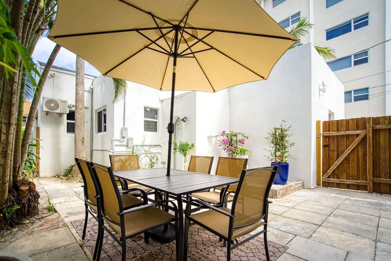Eine Terrasse mit Tisch, Stühlen, einem Sonnenschirm und Kübelpflanzen.
