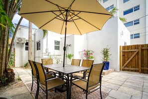A patio with a table and chairs, an umbrella, and potted plants. - Casa Roselle 3 Bedrooms Beach access (HOLLYWOOD)