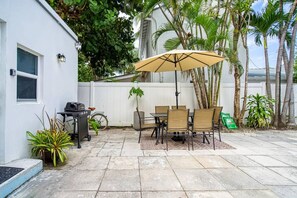 Une terrasse avec une table et des chaises, un barbecue et un vélo.