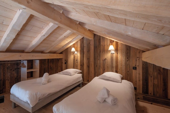 Una habitación con dos camas, paredes de madera y vigas en el techo.
