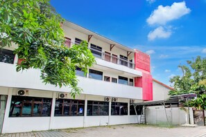 A two-story building with a white facade and red accents, featuring multiple windows and air conditioning units. - Hotel O J Ruby Hotel (Sewon)