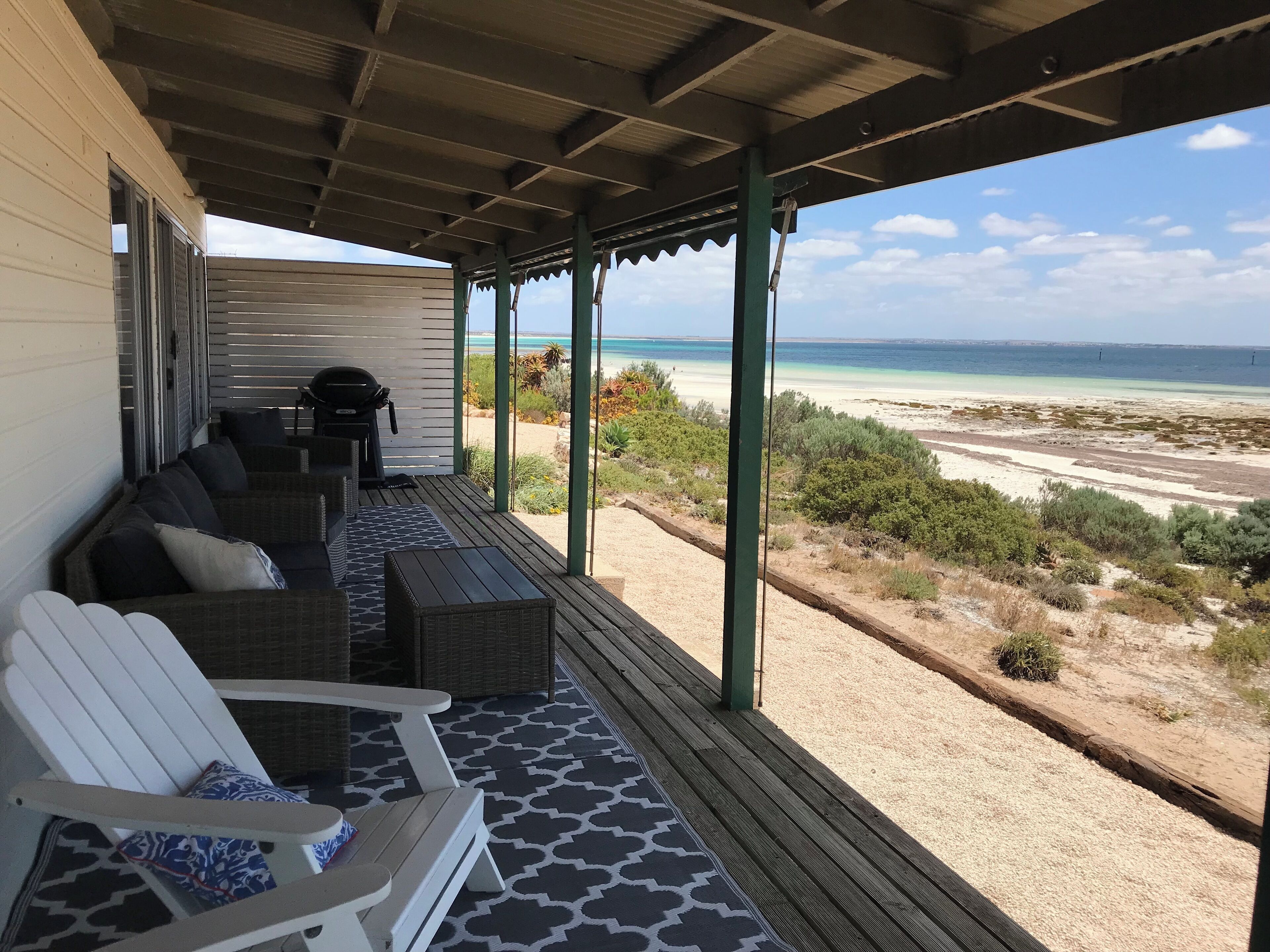A covered outdoor seating area with wicker furniture and a view of the beach.