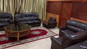 Une pièce avec deux canapés en cuir, une table basse en verre et un tapis à motifs.
