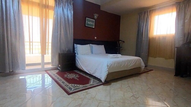 Une chambre d’hôtel avec un lit, une table de chevet, un tapis à motifs rouges et blancs et un tableau au mur.