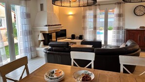Una sala de estar moderna con un sofá seccional, una mesa de comedor con platos y tazones, un televisor y una chimenea.