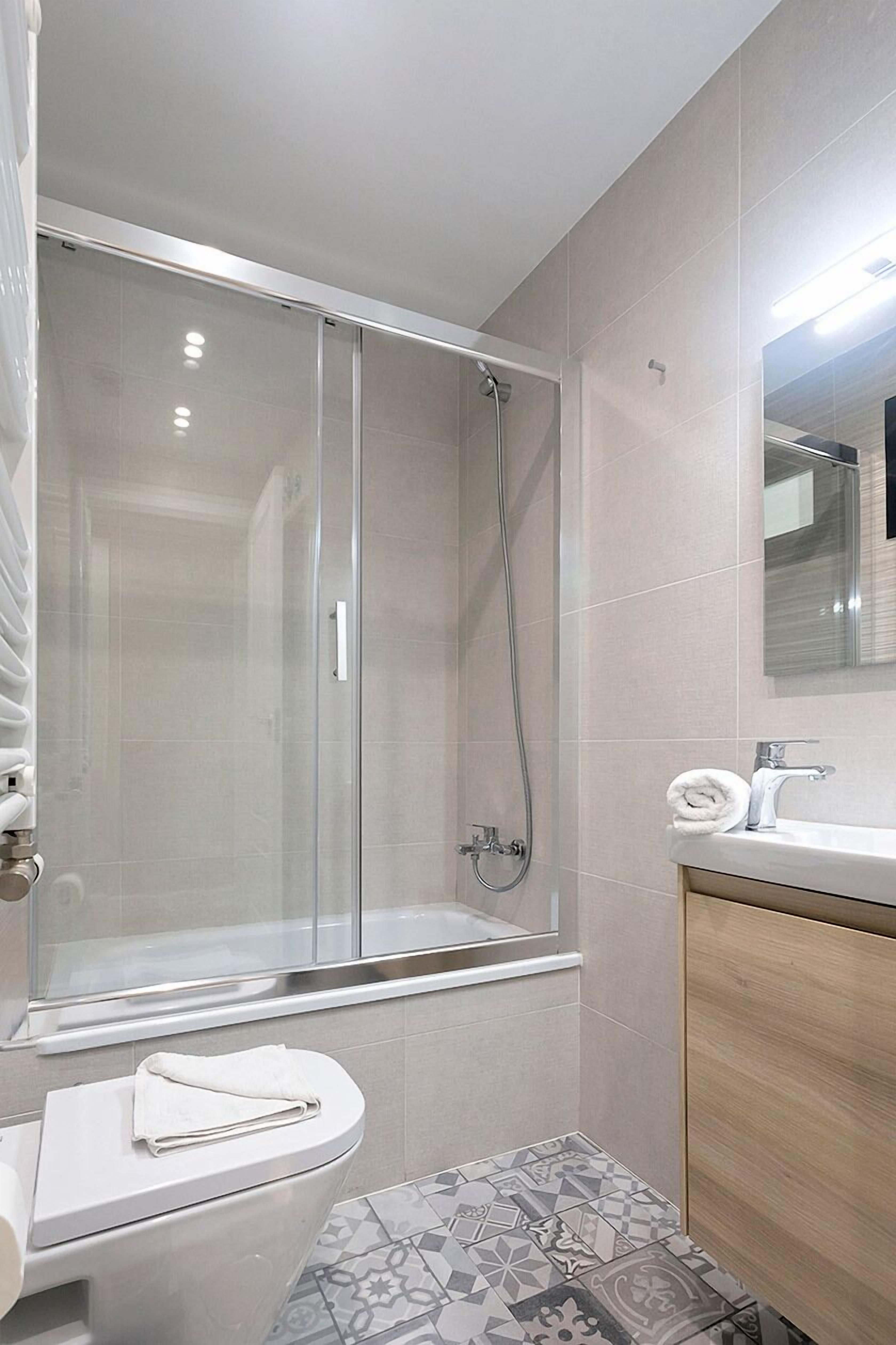 Une salle de bain moderne dotée d’une douche à parois de verre, de toilettes et d’un lavabo avec un meuble-vasque en bois.