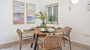 A dining area with a round wooden table, four wicker chairs, a vase with plants, and two framed artworks on the wall. - Genteel Home San Pablo Terrace (Córdoba)