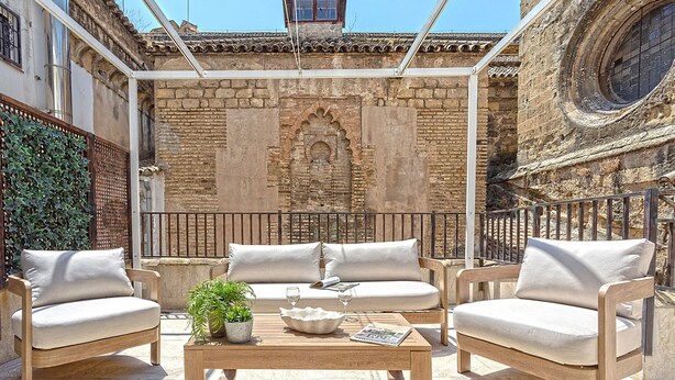 An outdoor seating area with two cushioned chairs, a wooden table, and a potted plant. - Genteel Home San Pablo Terrace (Córdoba)