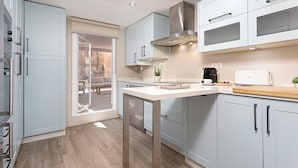 A modern kitchen with light blue cabinets, a stainless steel range hood, and a large window overlooking a balcony. - Genteel Home San Pablo Terrace (Córdoba)