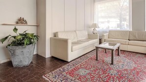 A living room with a beige sofa, a coffee table, a patterned rug, a potted plant, and a decorative plate on the wall. - Hotiday Celle Ligure (Celle Ligure)