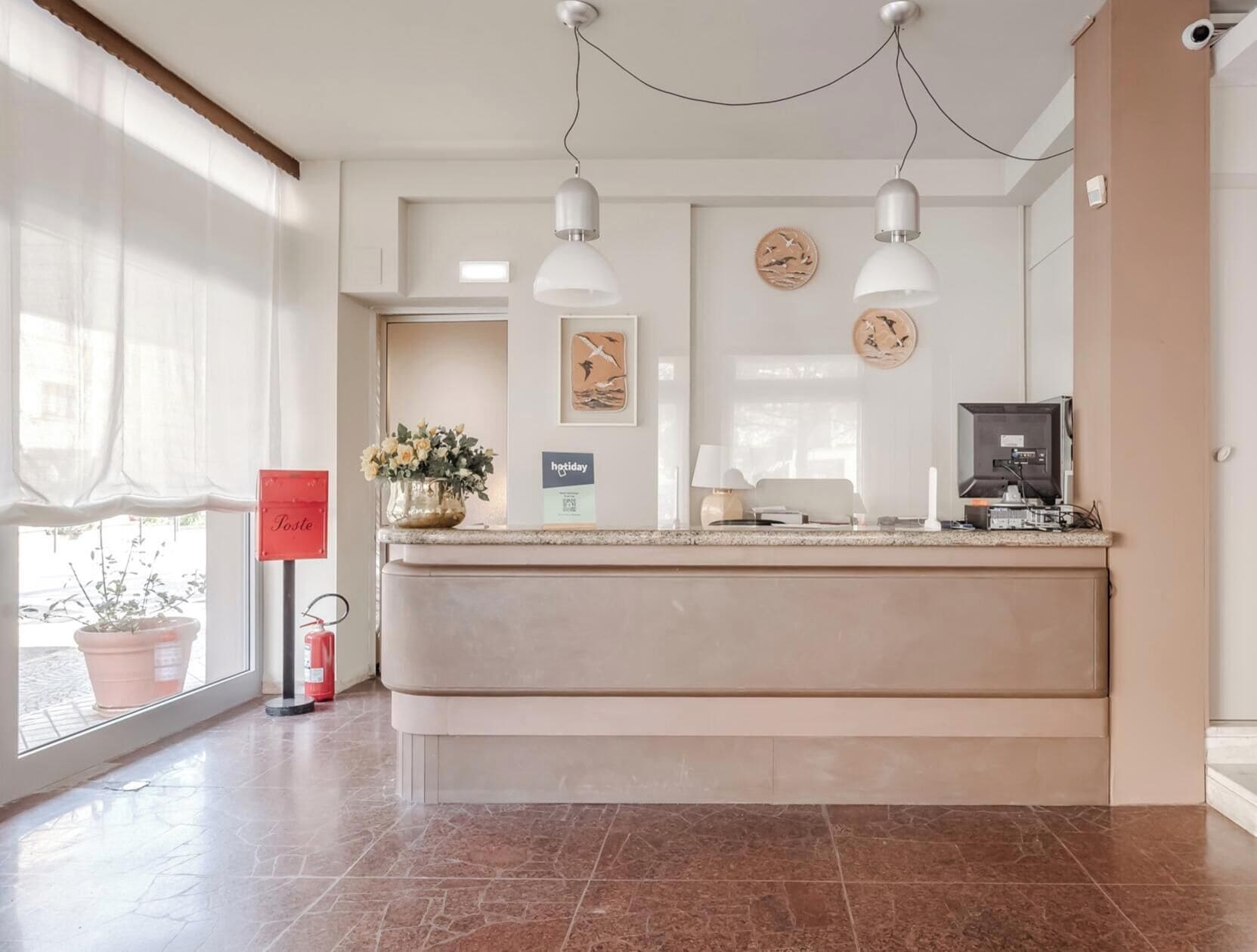 A reception area with a counter, two pendant lights, a potted plant, and a sign that reads 'Tostes.'