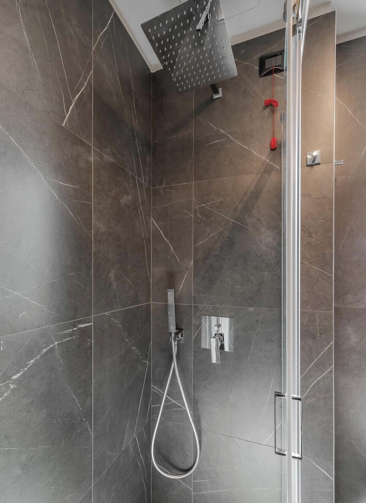 A modern shower with a handheld showerhead and a wall-mounted control panel.