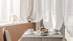 A table with a white tablecloth, two white cups, a plate with croissants, and a small bowl of jam. - Hotiday Celle Ligure (Celle Ligure)