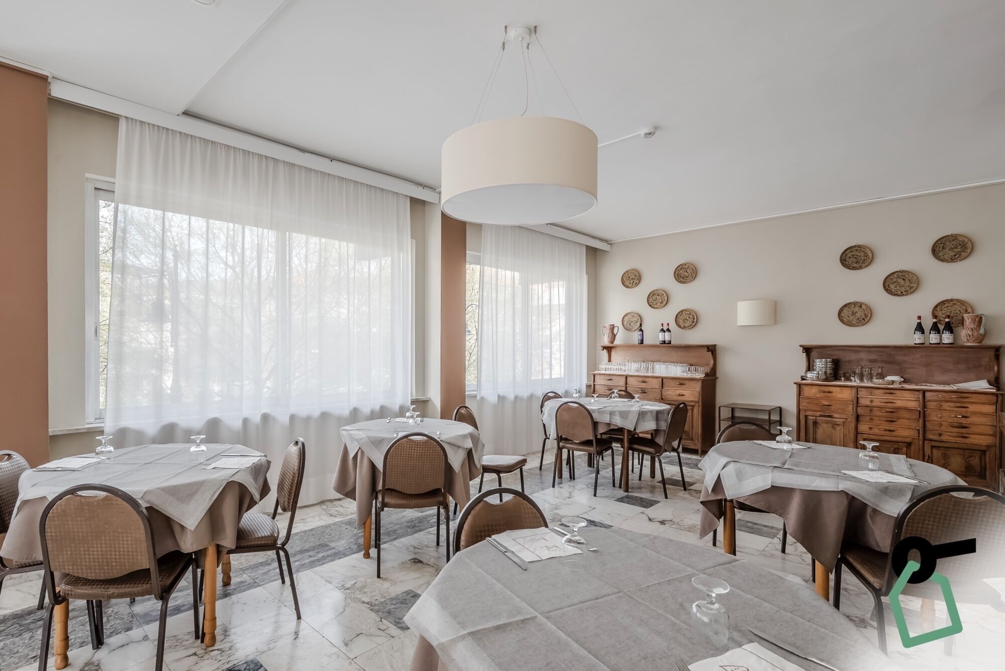 A dining area with round tables, chairs, and a chandelier.
