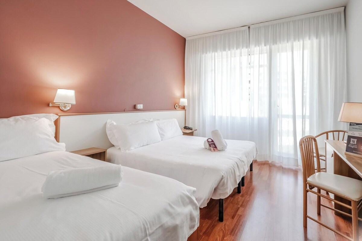 Habitación de hotel con dos camas, un escritorio y una silla.