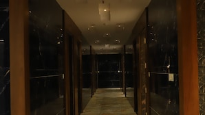 A corridor with marble flooring and wooden columns, leading to a dark room. - Hotel Shree Darshnam (Mathura)