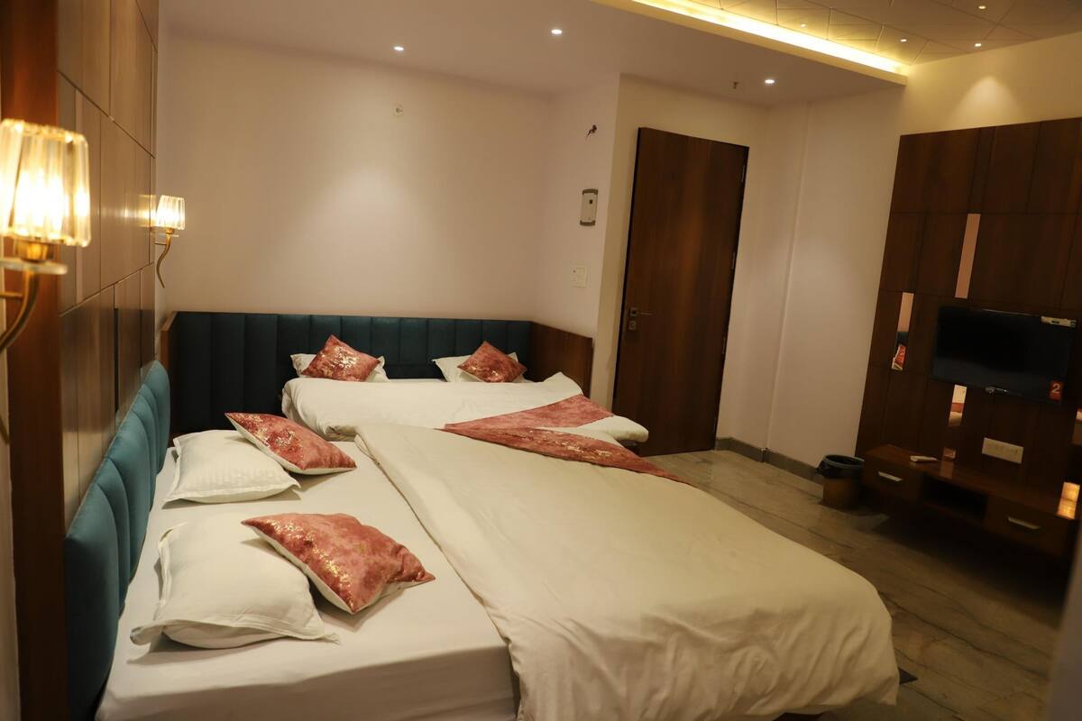 A hotel room with two beds, a TV, and a wardrobe.