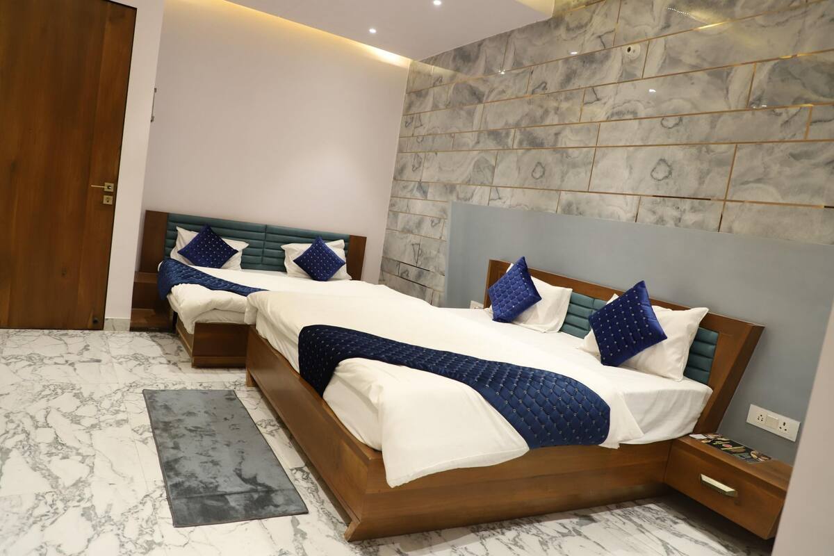 A hotel room with a large bed, bedside tables, a wooden wardrobe, and a marble-patterned wall.