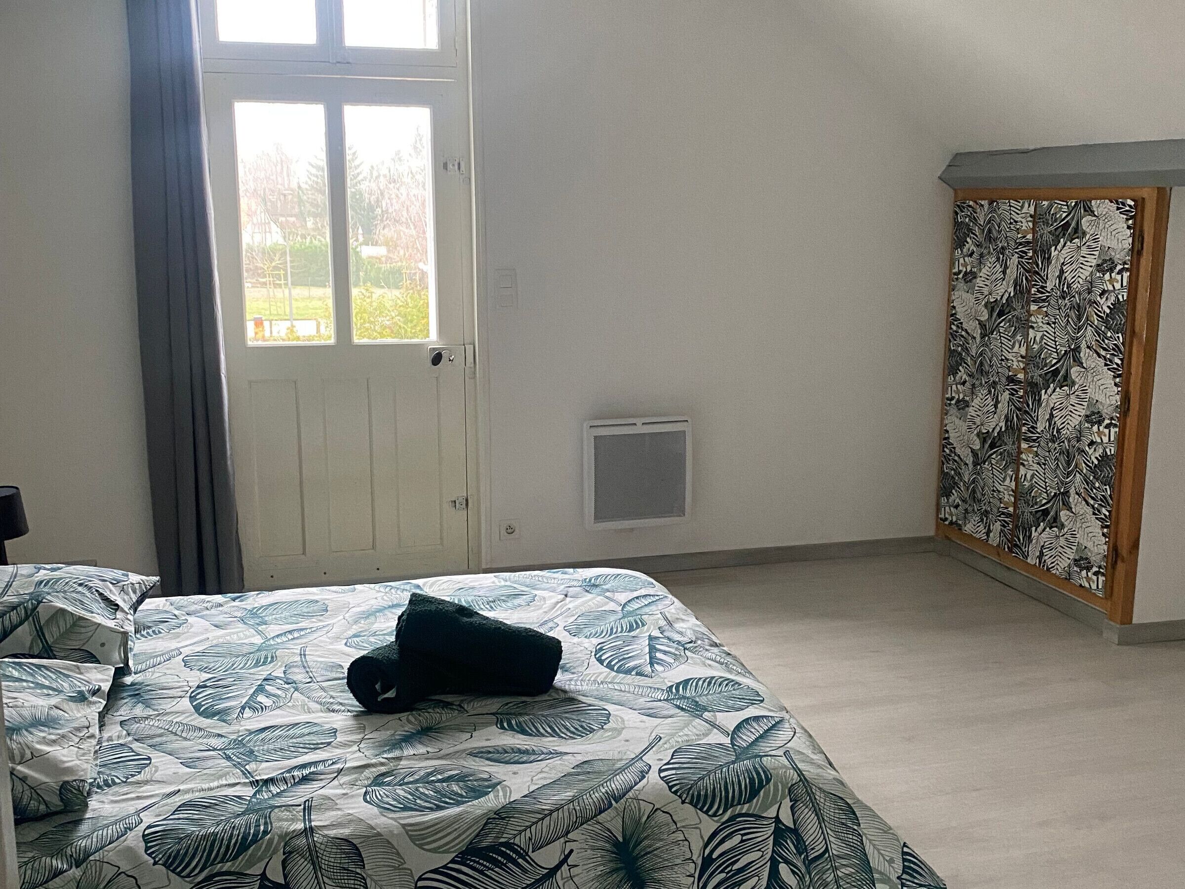 A bedroom with a bed, a window, a door, and a wardrobe.