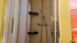 En dusch med ett duschhuvud som kan hållas i handen, en väggmonterad blandare och ett duschhuvud som kan hållas i handen.
