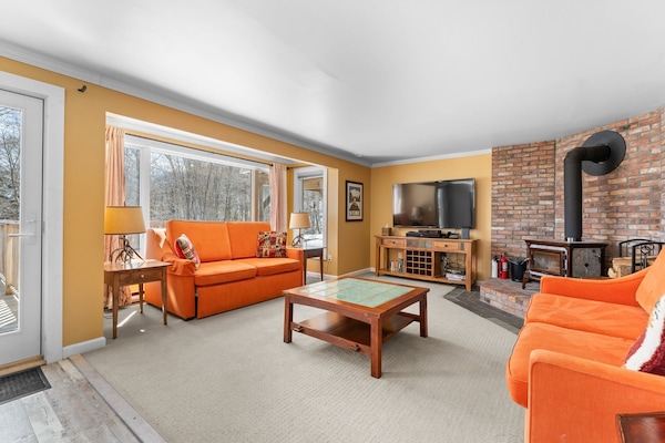 The living room of this upscale ski-on ski-off Killington condo features a wood-burning stove and a smart TV with premium cable.