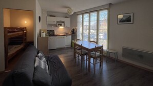 A compact living space with a kitchenette, a dining area with a table and chairs, a sofa, and a bunk bed. - Charming 2-bedroom apartment in Cauterets (Cauterets)