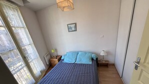 A bedroom with a bed, two bedside tables, a window, and a door. - Charming 2-bedroom apartment in Cauterets (Cauterets)